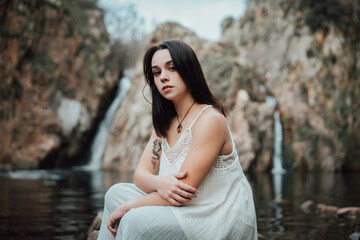 Joven modelo con vestido blanco posa dentro de un lago