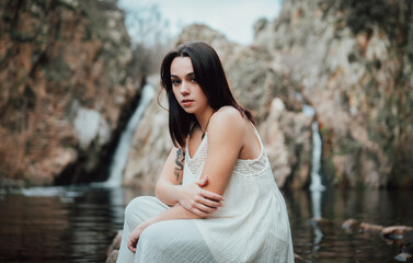 Joven modelo con vestido blanco posa dentro de un lago