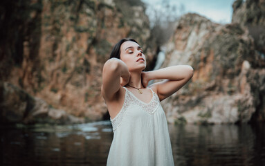 Joven modelo con vestido blanco posa dentro de un lago