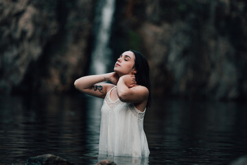 Joven modelo con vestido blanco posa dentro de un lago