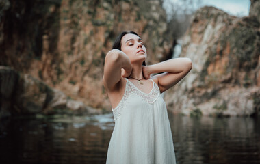 Joven modelo con vestido blanco posa dentro de un lago