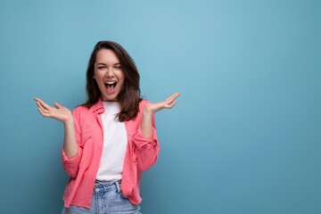 happy lucky brunette woman in informal look rejoices on studio background