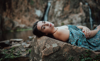 Modelo joven con vestido azul posa en un lago