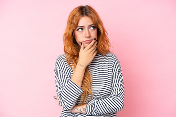 Young caucasian woman isolated on pink background having doubts and with confuse face expression