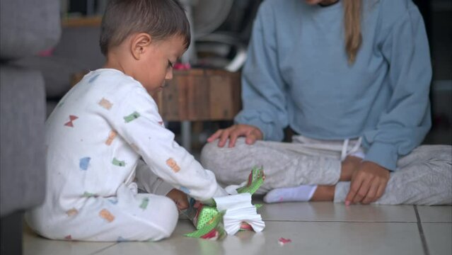 Slow Motion Close Up Of A Young Hispanic Boy Wearing Pajamas Opening His Christmas Presents With His Mom On The Floor