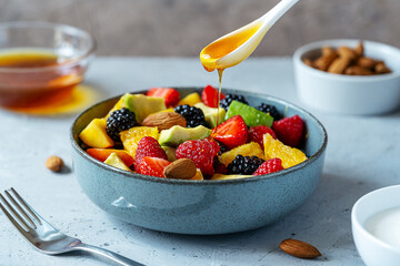 Healthy fruit salad in a grey bowl made with avocado, strawberry, raspberry, orange, blackberry,...