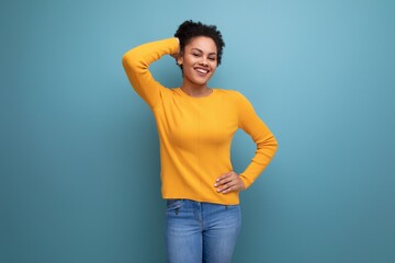pretty confident 20s latin woman with afro hair in casual yellow sweater on studio background with copy space