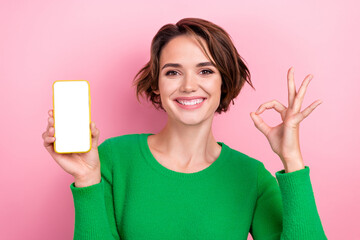 Photo of sweet charming lady wear green pullover showing okey holding iphone samsung apple gadget isolated pink color background