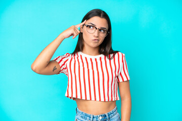 Young caucasian woman isolated on blue background making the gesture of madness putting finger on...