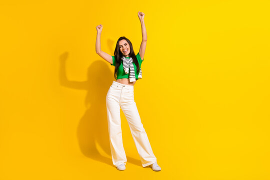Full length photo of cheerful lucky lady wear white pants shouting rising fists isolated yellow color background