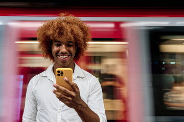 young african american man standing in Subway using smartphone