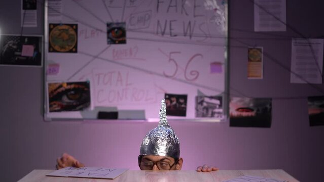 Strange man conspiracy theorist in protective foil cap with all seeing eye. Fake news