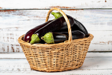 Fresh raw eggplant in a basket over wooden background. Eggplant harvest season concept. Vegetables for a healthy diet