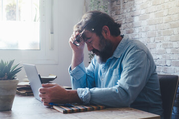 Tired man in front of laptop touching head with closed eyes. Modern smart working freelance...