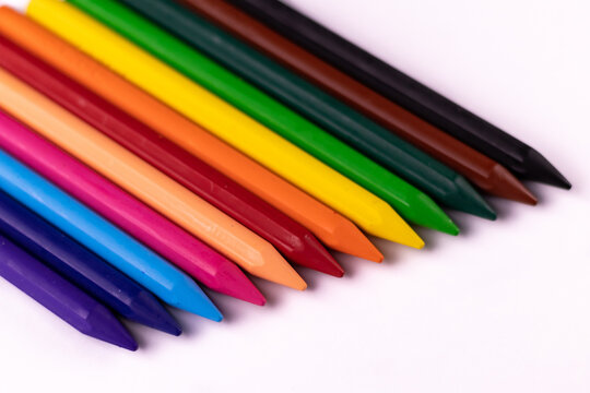 High angle close up shot of crayon color sticks put on white background placed laterally adjacent to each other.