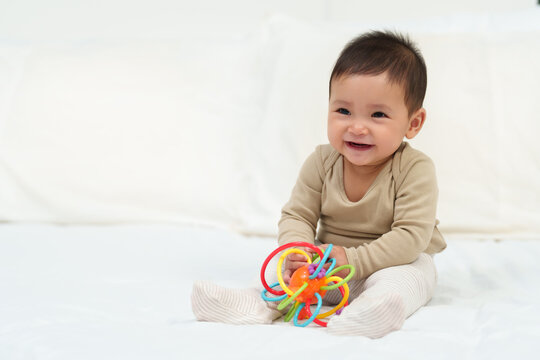 infant baby playing with colorful rubber bites toy on bed