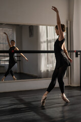 Fototapeta na wymiar A beautiful Asian ballerina is training in a dance class. Vertical photo.