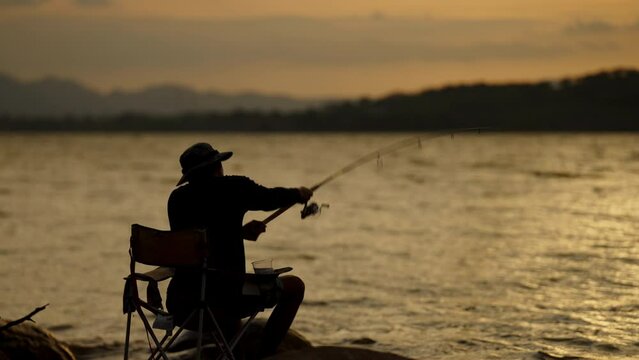 Silhouette of fishermen alone recreation with fishing rod outdoor catching lifestyle fish at sunset