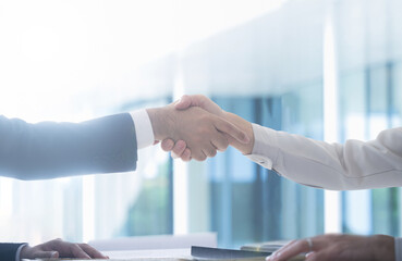 Man in suit and man in work clothes shaking hands in business Contract scene, etc.