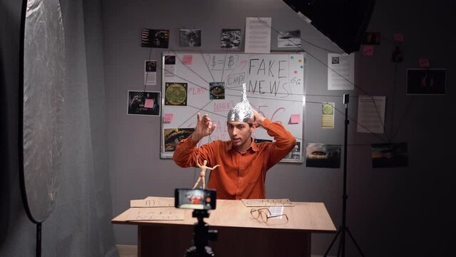 Young male conspiracy theorist in a protective foil cap and glasses debunks myths. Conspiracy theory. Concept of world conspiracy, world government, manipulation, world control