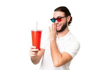 Young handsome man holding soda while watching a 3D movie over isolated chroma key background with...