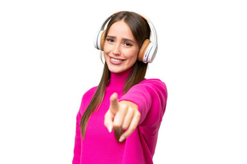 Young beautiful caucasian woman over isolated background listening music and pointing to the front