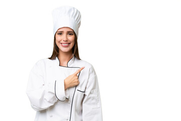 Young chef caucasian woman over isolated background pointing to the side to present a product