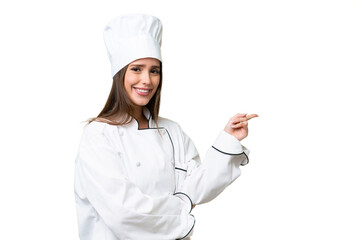 Young chef caucasian woman over isolated background pointing finger to the side