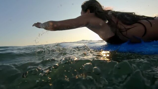 Surfing at Sunset. Outdoor Active Lifestyle. Portrait of surfer woman surfing having fun on Bali, Indonesia. Female bikini girl in water during surfing surfboard smiling happy living healthy lifestyle
