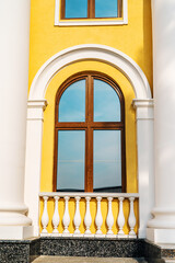 Fragment of the facade of a house in retro style with an arched window and plaster columns. Close-up. vertical photo