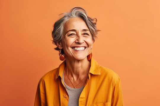 Portrait Of A Smiling Senior Woman Looking At Camera Isolated Over Orange Background