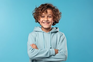 Portrait of a smiling little boy in a blue hoodie on a blue background - obrazy, fototapety, plakaty