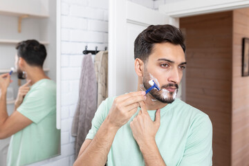 Handsome man shaving in the bathroom. Morning routine concept
