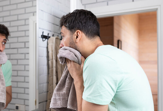 Handsome man washing his face in the bathroom. Morning routine and hygiene concept	