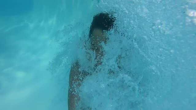 The boy dives into the pool has fun and swims underwater