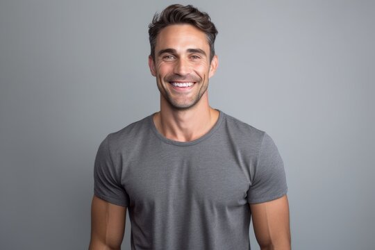 Portrait of a handsome young man smiling and looking at camera on grey background