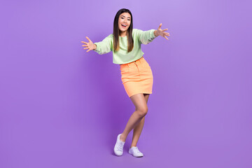 Naklejka premium Full size photo of satisfied good mood woman dressed green shirt stylish skirt stretching arms to you isolated on purple color background