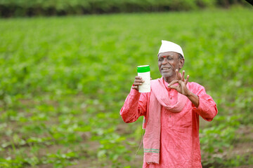 Fototapeta premium Indian happy farmer holding empty Bottle in hands, happy farmer showing white Bottle