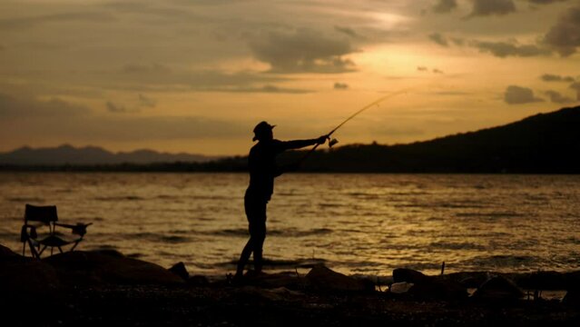 Silhouette of fishermen alone recreation with fishing rod outdoor catching lifestyle fish at sunset