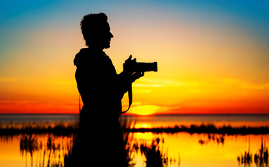 Silhouette woman photographing landscape at sunset - 625880412