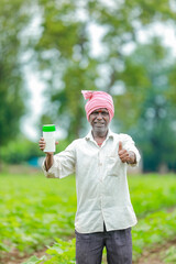 Fototapeta premium Indian happy farmer holding empty Bottle in hands, happy farmer showing white Bottle