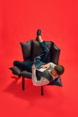 Businessman, employee sitting on armchair in weird, uncomfortable position, working on laptop...