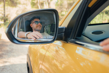 Rear view mirror view of a Latino man with sunglasses driving in the car