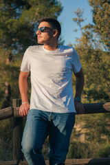 Latin man posing with a sunglasses and a white shirt at sunset