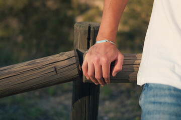 Hand of a man with a silver bracelet at sunset - obrazy, fototapety, plakaty