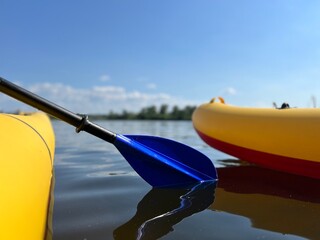 Fototapeta na wymiar Paddle in the tourist's hand in the water between kayaks