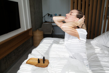 the woman uses essential oils and enjoying fragrance in the morning sitting in bed. Aroma therapy
