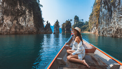 Traveler asian woman relax and travel on Thai longtail boat in Ratchaprapha Dam at Khao Sok National Park Surat Thani Thailand - obrazy, fototapety, plakaty