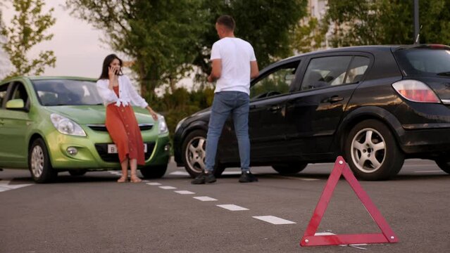 Red emergency stop triangle sign afore Destroyed car in car crash traffic accident on city road. Man driver looking on Smashed broken car in accident. Copy space.