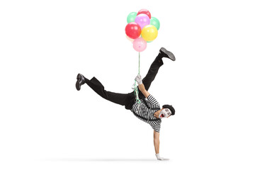 Mime doing a hand stand and holding a bunch of balloons